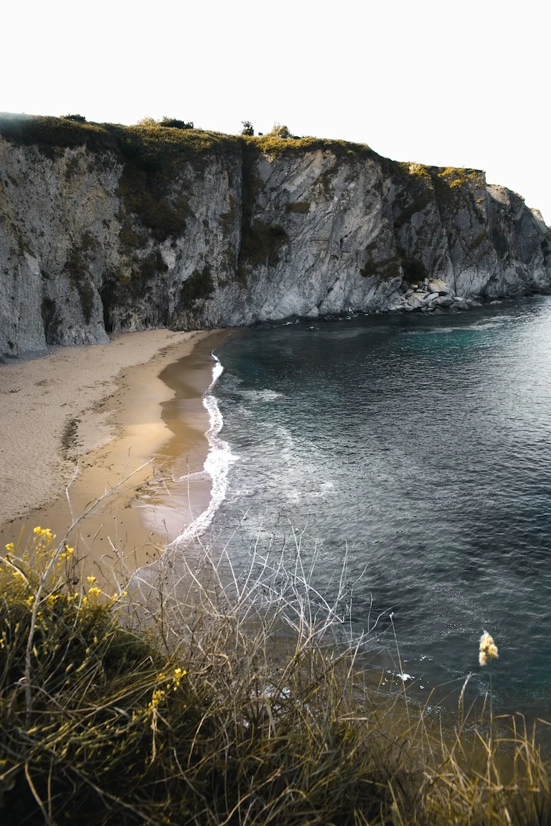 Arena dorada y acantilados blancos en la playa de Covachos, Cantabria