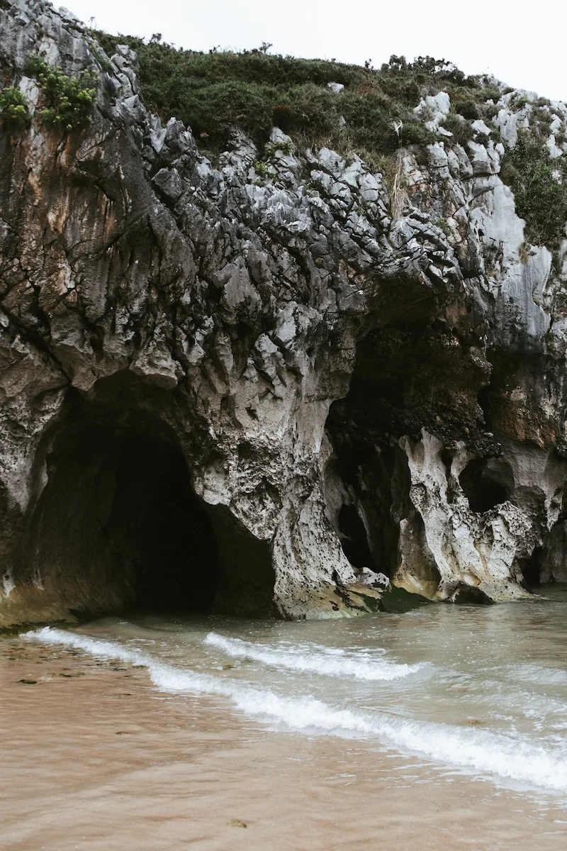 Entrada a las cuevas de roca caliza en la Playa de Cuevas del Mar, Asturias