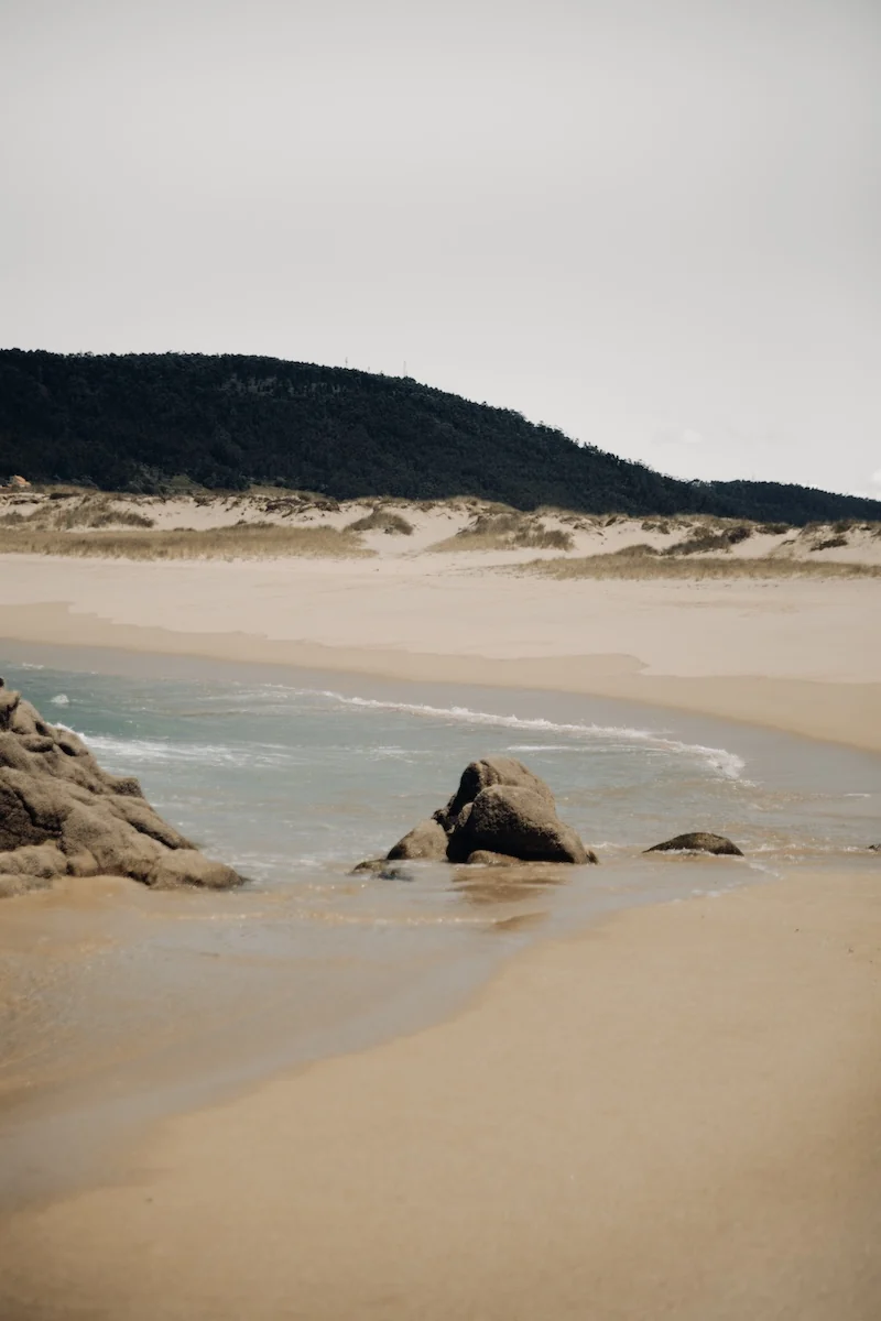 Extensa playa de Doniños con sistema dunar y montañas al fondo, en Galicia