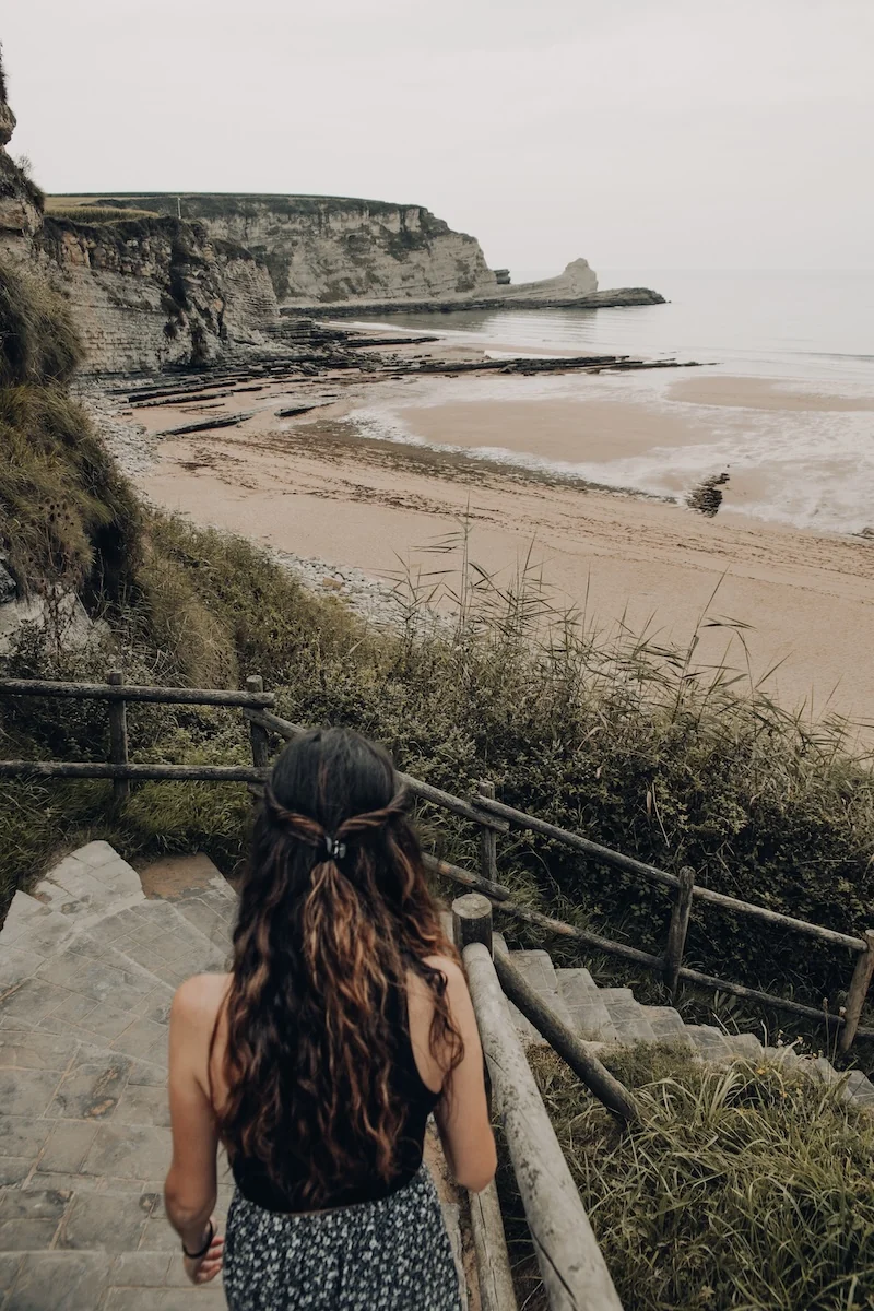 Vista desde las escaleras hacia la playa de Langre, rodeada de acantilados en Cantabria
