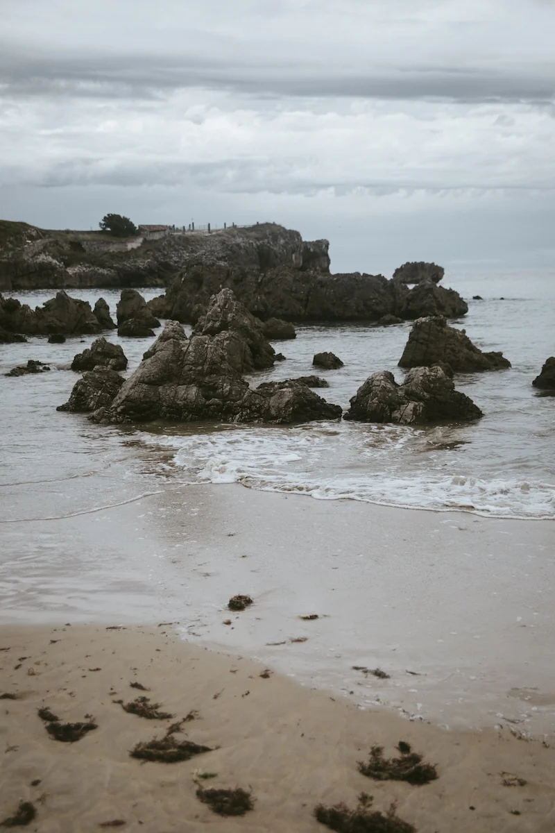 Rocas puntiagudas emergiendo en la orilla de la Playa de Toró, Llanes, Asturias